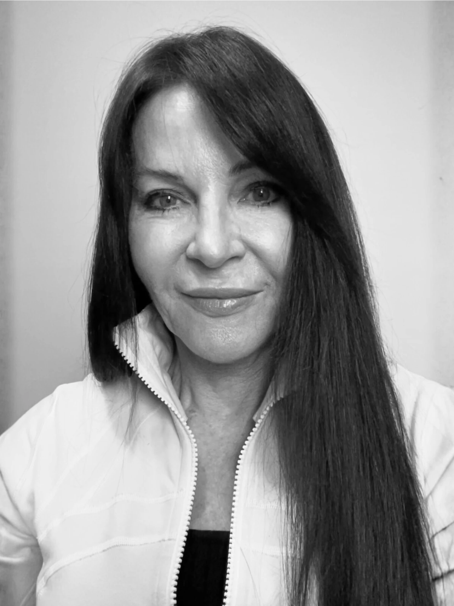 A headshot of Jan Stockton with long dark hair, wearing a zippered jacket and looking at the camera with a gentle smile.